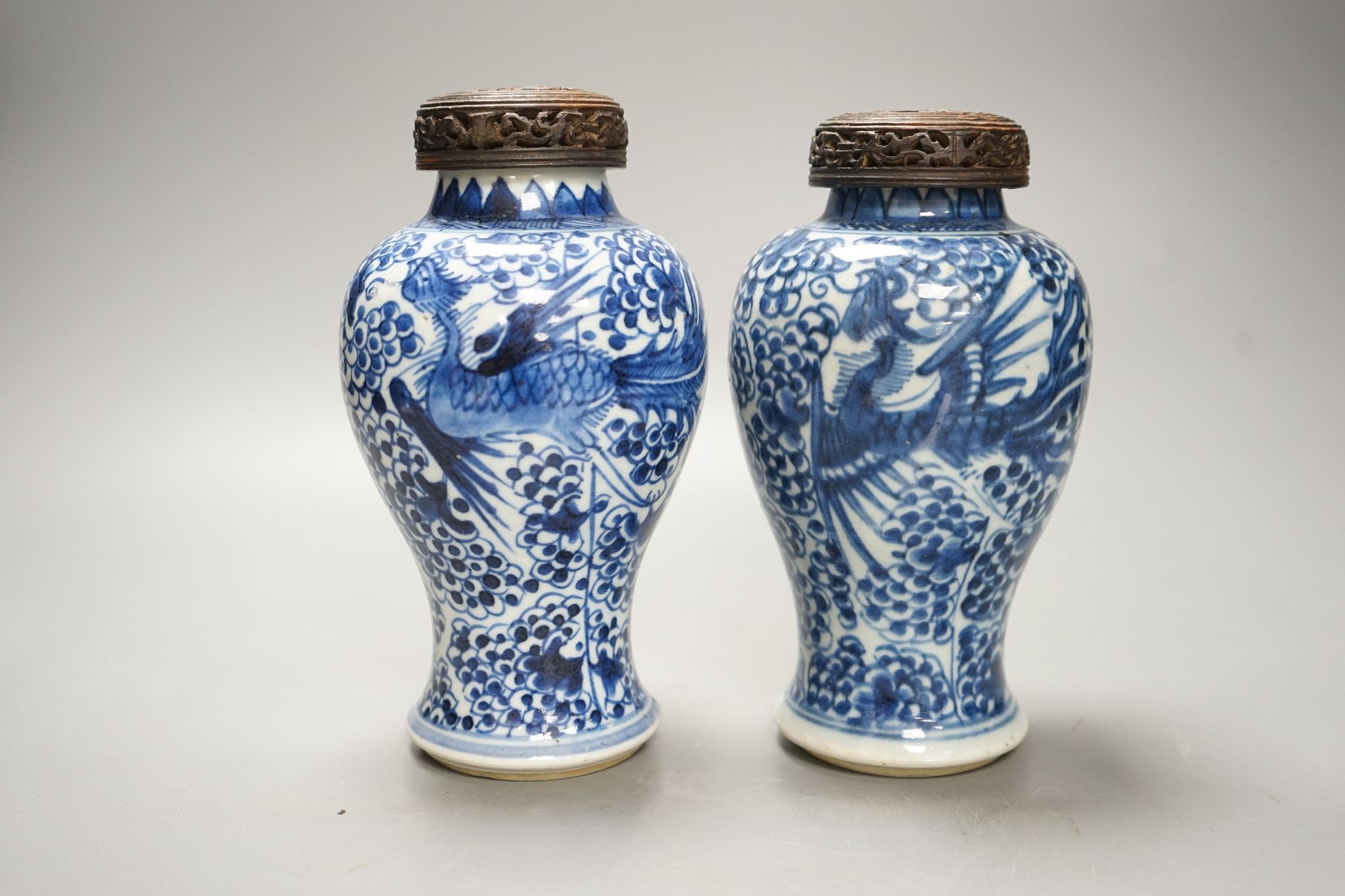 A pair of Chinese blue and white 'phoenix' vases, Kangxi, associated wood covers, 19cm including covers